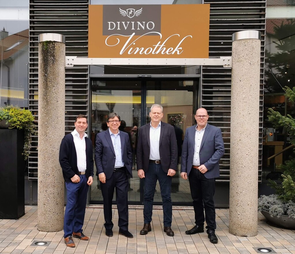Pressefoto mit fünf Personen vor dem Eingang der Divino-Vinothek mit Logo-Schild.